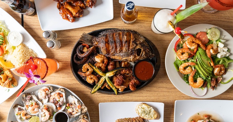 Mexican seafood feast with grilled whole fish, shrimp salad, oysters, and drinks