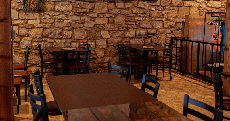 Interior, tables and chairs near stone covered wall