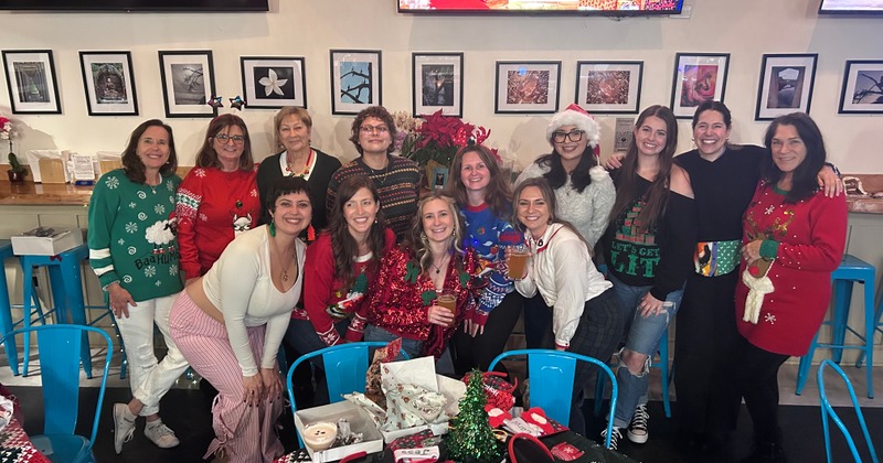 Group of people wearing holiday-themed sweaters while posing together