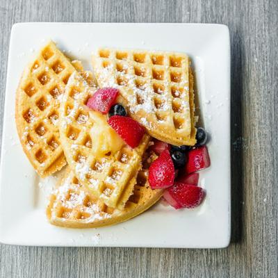 Plate of waffles topped with berries and powdered sugar.