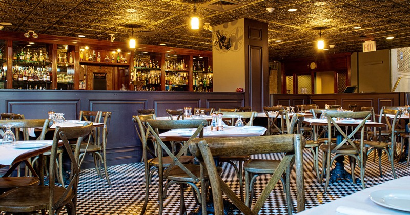Interior, vintage wooden chairs and tables, tile decorated ceiling, bar in the back