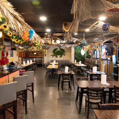 Interior with tables, chairs, a tiki bar, and nautical decorations.
