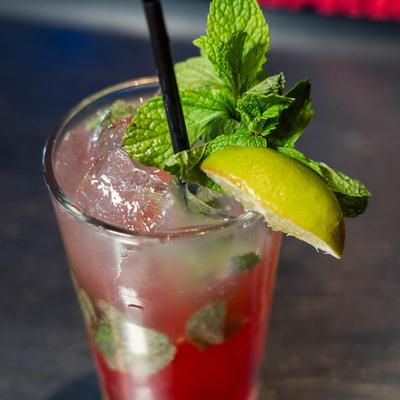 A glass of cranberry mojito, garnished with mint and lime.