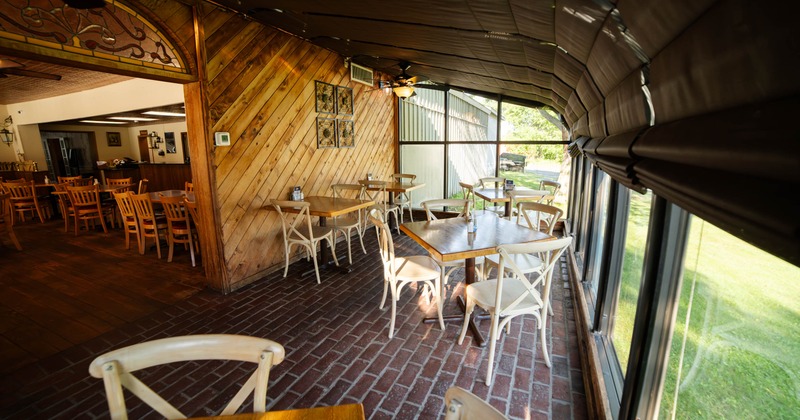 A cozy restaurant dining area with wooden accents, large windows, and wooden tables and chairs