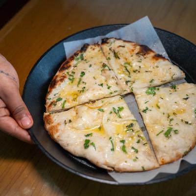 Cheese naan sliced and served on a black plate.