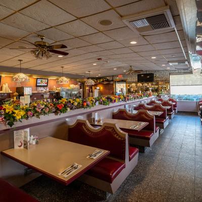 Diner interior featuring red booths, floral decorations, and ceiling fans.