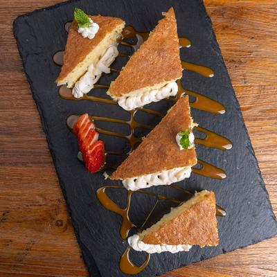 Tres leches cake slices on black slate board.