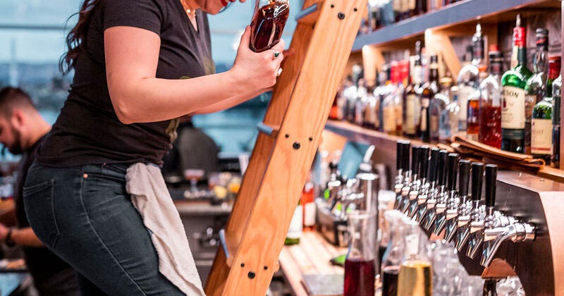 Back bar, an employee using ladder to get liquor from the shelves