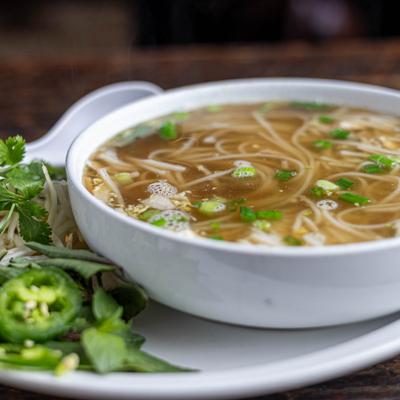 Chicken Pho with birds eye chili peppers and fresh herbs on the side.