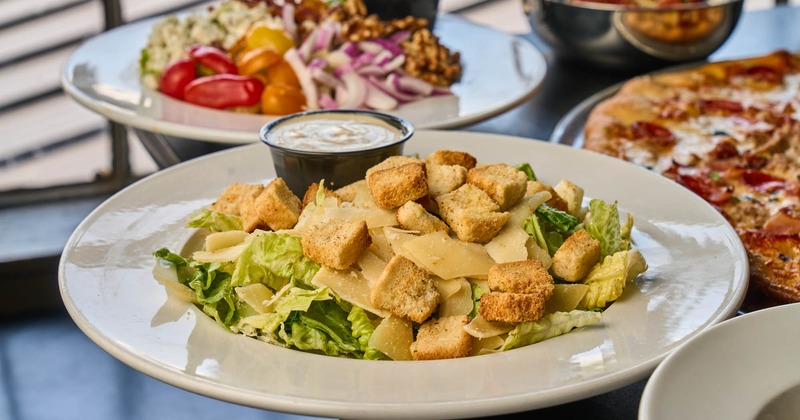 Side Caesar salad with a cup of dressing