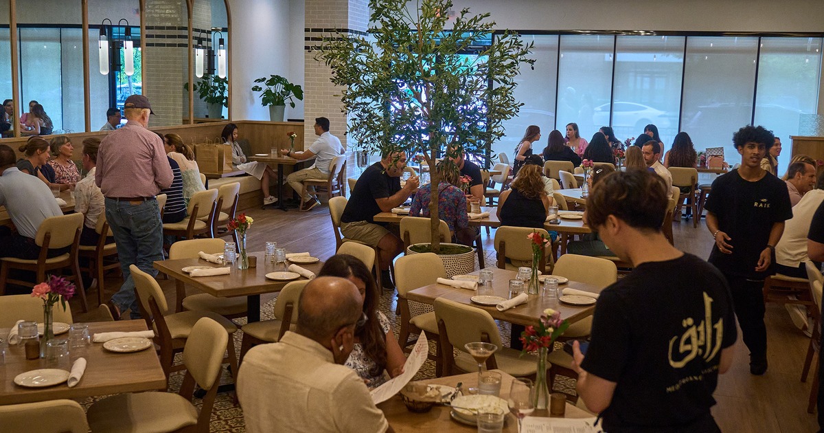 Lively atmosphere in a dining area, with seated guests and staff in action