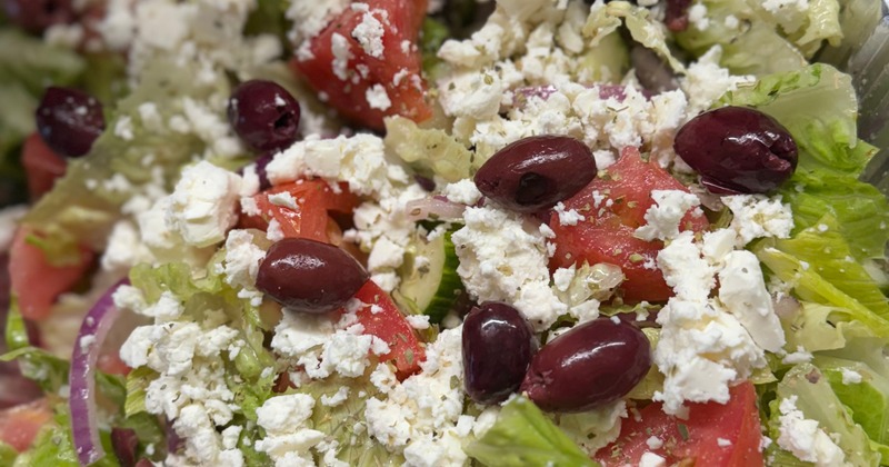Greek salad with olives and feta cheese in a foil tray
