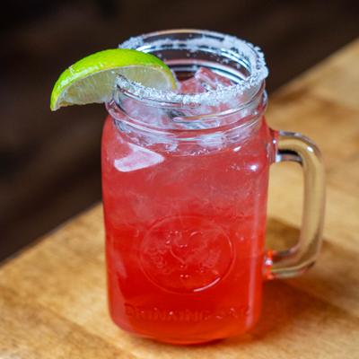 Strawberry Margarita served in a mason jar, garnished with a lime slice.