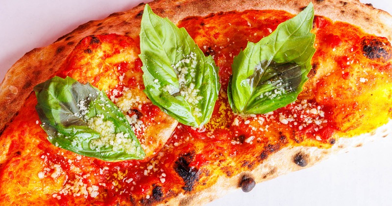 Calzone topped with tomato sauce, Parmesan, and fresh basil leaves