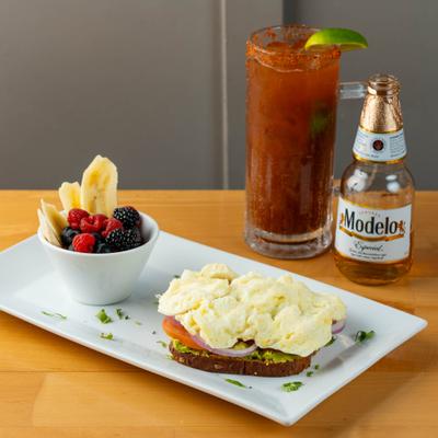Avocado Toast with scrambled eggs, cup of fruit, beer, and a Michelada.