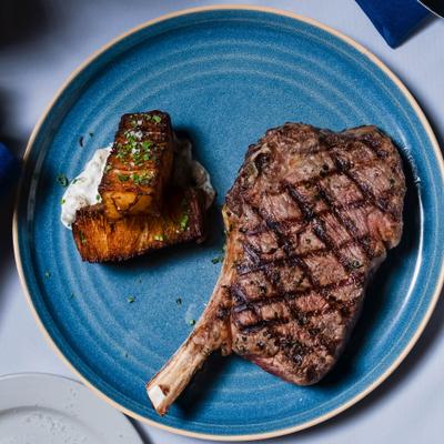 Grilled steak served with crispy potatoes on a blue plate.