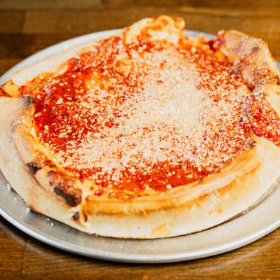 Deep dish pizza with tomato sauce and grated Parmesan.
