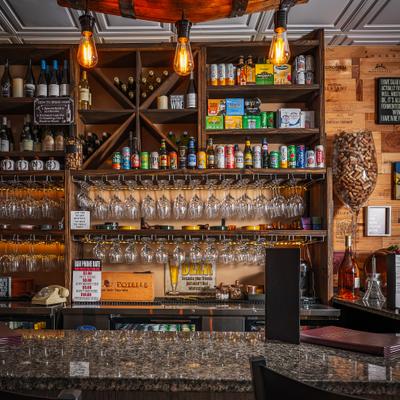 Wine bar counter lined with glasses and shelves.