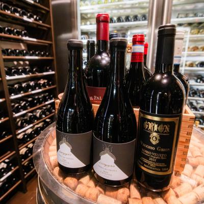 Wine bottles arranged on a cork-filled barrel display in a wine cellar.
