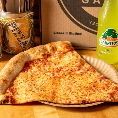 A large cheese pizza slice sits on a plate next to lime soda.