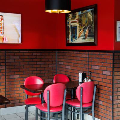 Four-seat dining table with red chairs and wall art.
