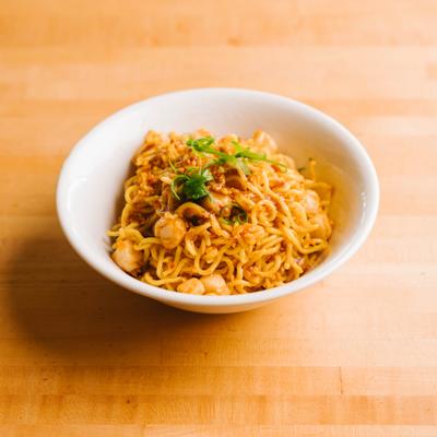 Scallop noodles in a bowl with herbs.