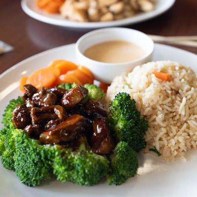 Teriyaki steak bites served with rice, broccoli, carrots, and creamy sauce.