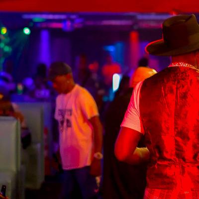 A colorful bar scene with vibrant neon lights, People socialize.