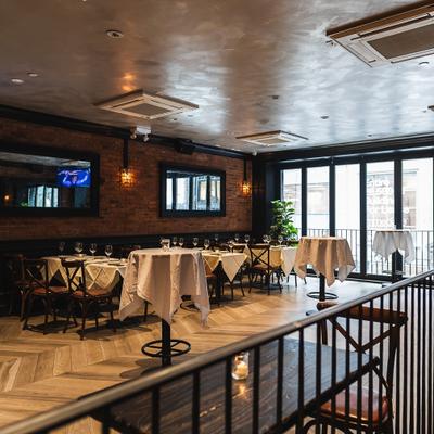 Interior featuring seating area, dark brick walls, wooden floors and large windows.
