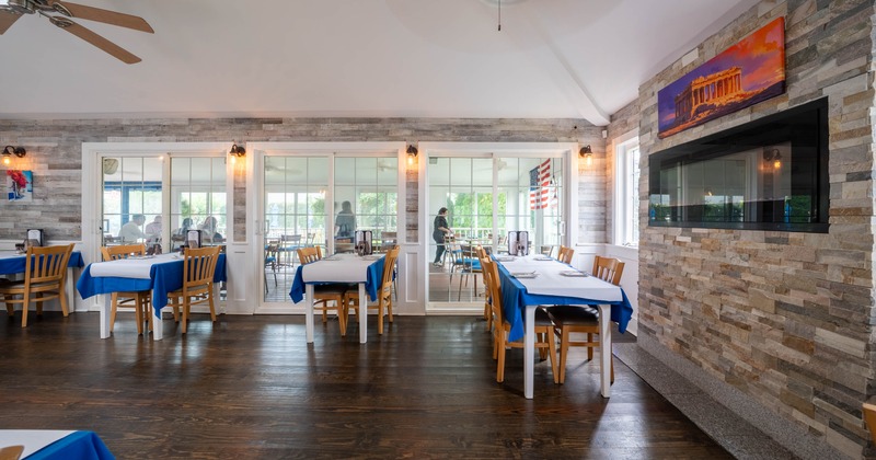 Interior, wooden floors, blue and white table settings, large windows, artwork, electric fireplace