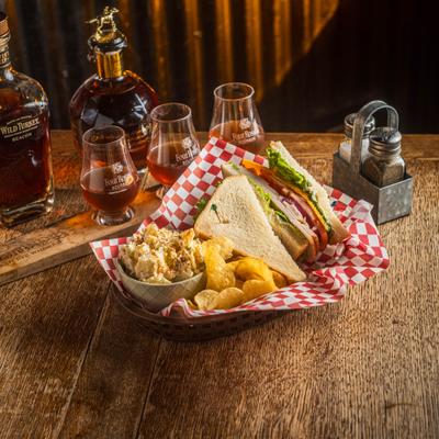 Smoked turkey sandwich paired with chips, potato salad and a whiskey flight.