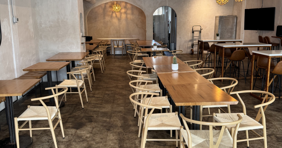 Spacious modern cafe with wooden tables and light wicker chairs arranged neatly