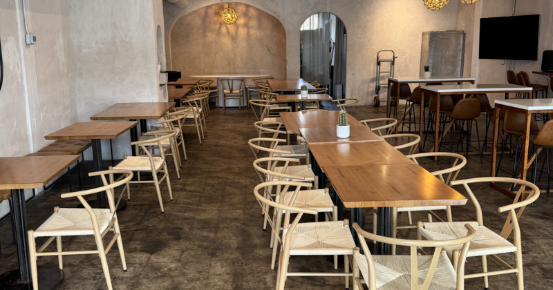 Spacious modern cafe with wooden tables and light wicker chairs arranged neatly