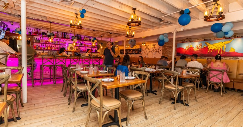 Interior, bar and dining area with place settings on tables, guests dining