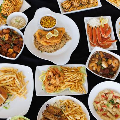 Overhead view of assorted seafood dishes with fries and sides.