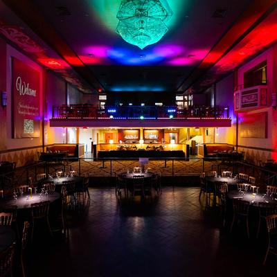 An expansive room filled with tables and chairs, with partitioned bar and dining areas.