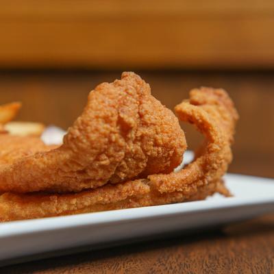 Golden-brown fried fish served on a plate, close-up.
