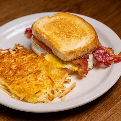 Egg and bacon toast sandwich with hashbrowns on the side.