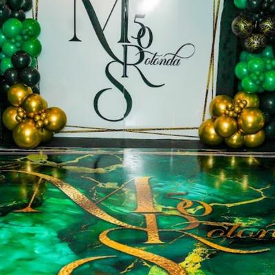 Elegant emerald and gold ballroom decor featuring balloons and marble dance floor.