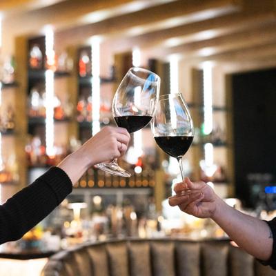 Two hands holding and clinging glasses of red vine.