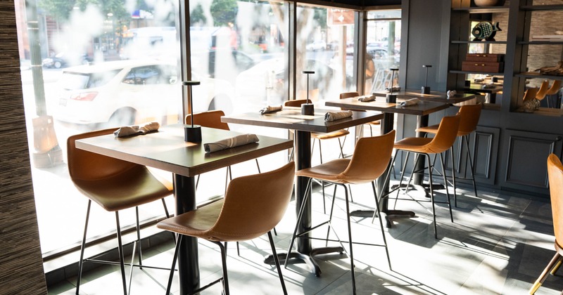 Interior, high seating area, wooden top tables with stools for two, large shop window