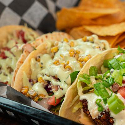 Tacos topped with corn, scallions, and crema.