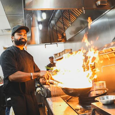 Chef preparing food in a frying pan.