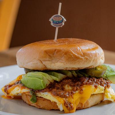 Breakfast sandwich with avocado, egg, cheese, and pickles.