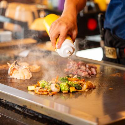 A chef cooking food in the teppanyaki style.