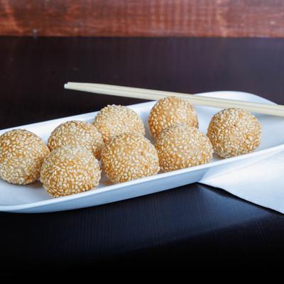 Sesame balls on a white plate with chopsticks.