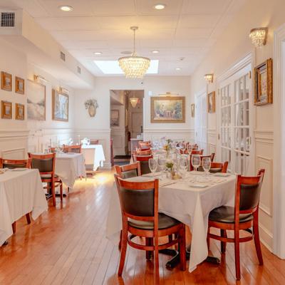 Upscale dining room with set tables, wooden floors, and a crystal chandelier.