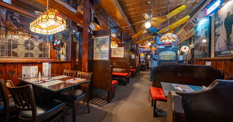 Interior of a cozy restaurant with wooden paneling, stained glass, and colorful pendant lights