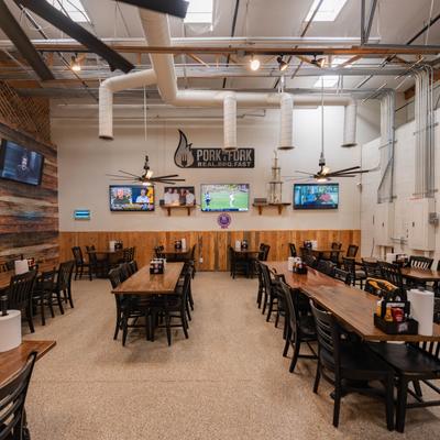 Seating area with large tables and TV screens on the walls.
