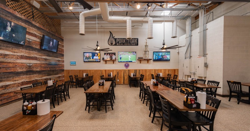 Seating area with large tables and TV screens on the walls